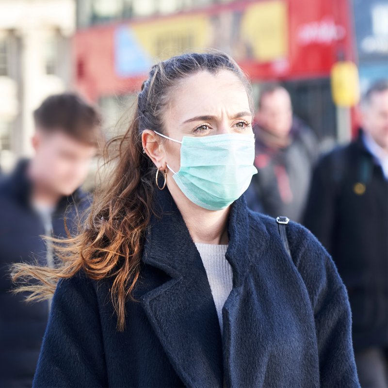 Una donna indossa una mascherina sul viso per le strade di una città
